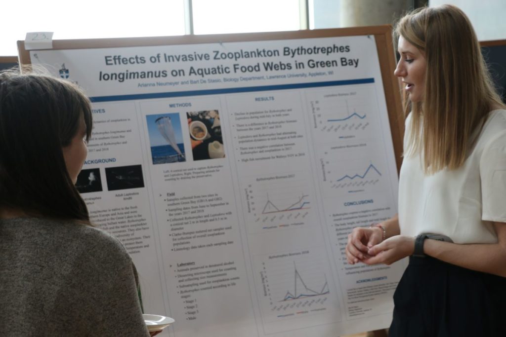 Biology major student looking at her poster while they present their research 