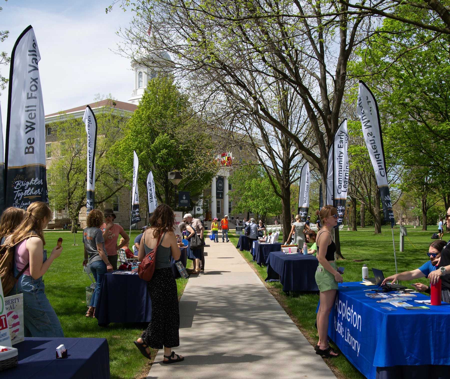 Community groups staff tables lined up on a sidewalk on Main Hall Green.