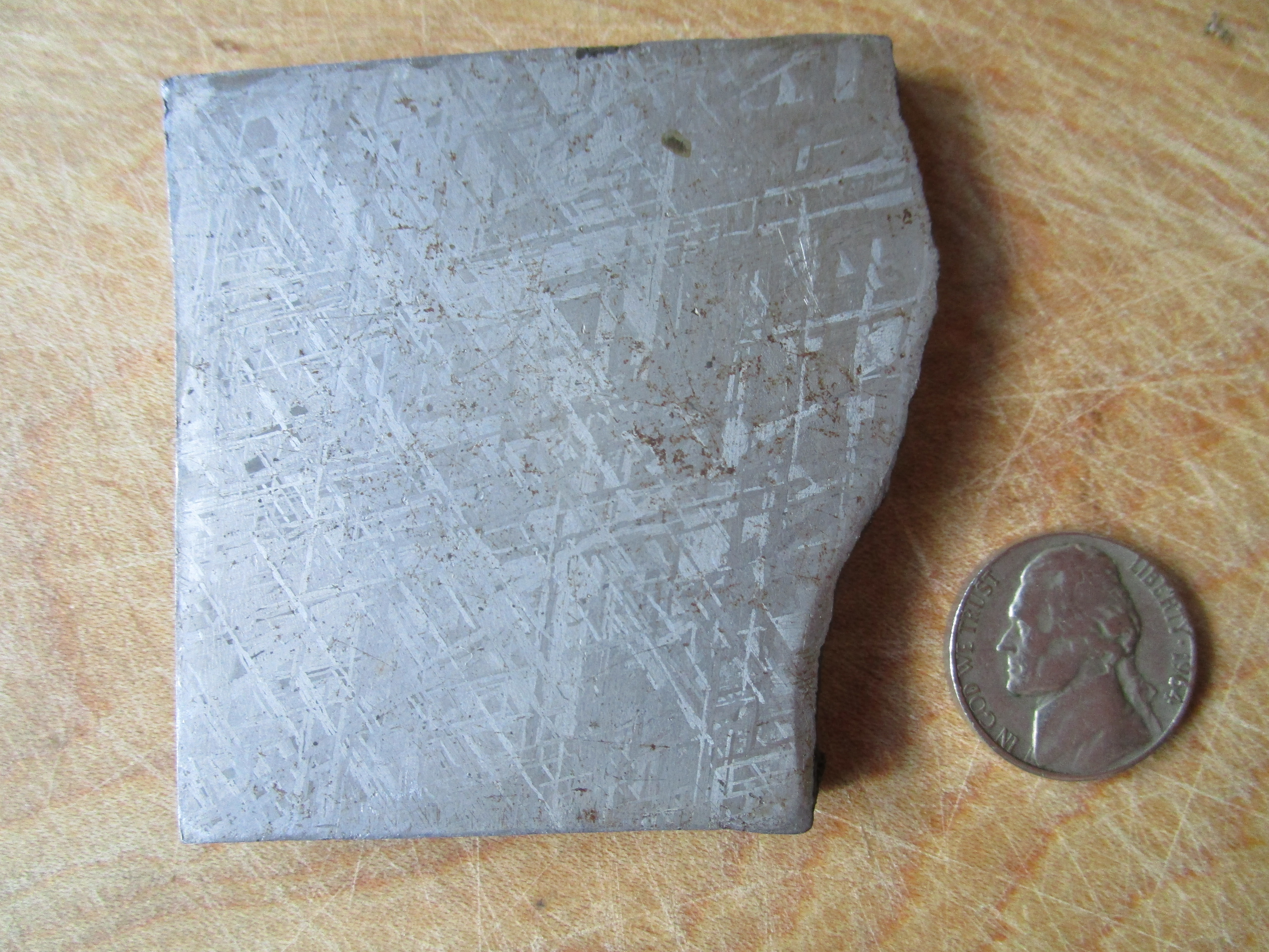 The meteorite fragment is shown next to a nickel for size comparison.