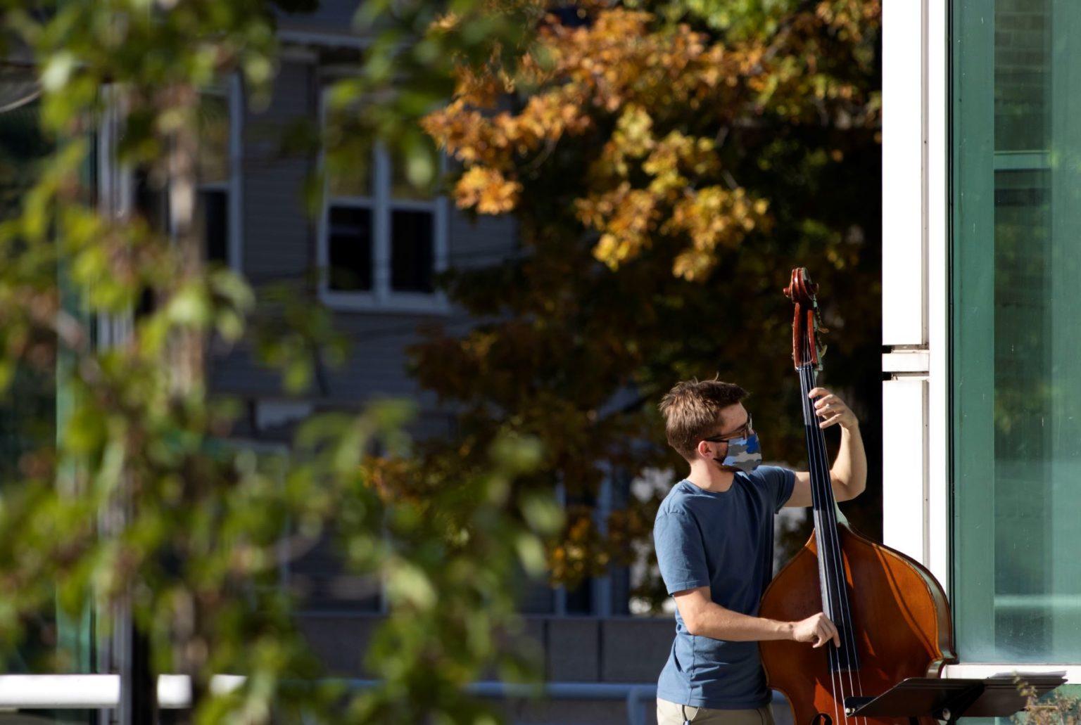 David Pickar ’23 plays an upright bass on the steps of Shattuck Hall