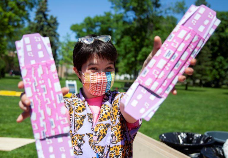Georgia Greenberg holds up two pink masks featuring symbols from LUaroo.