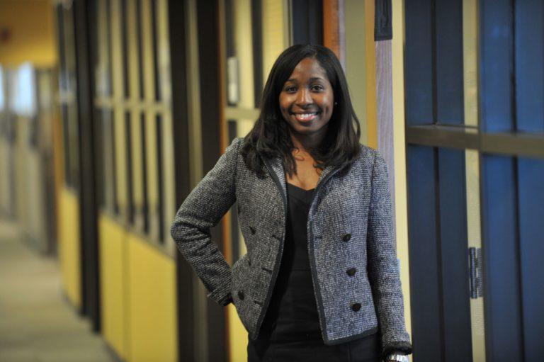 Andrea Lewis Hartung, wearing a grey blazer, smiles at the camera.