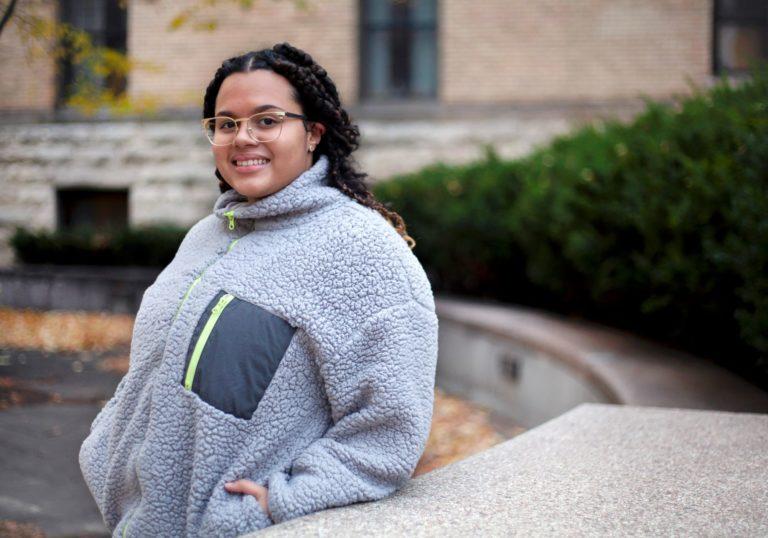 Meralis Alvarez, wearing a grey coat, smiles at the camera.