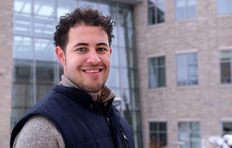Daniel Toycen, wearing a navy blue vest, smiles at the camera.