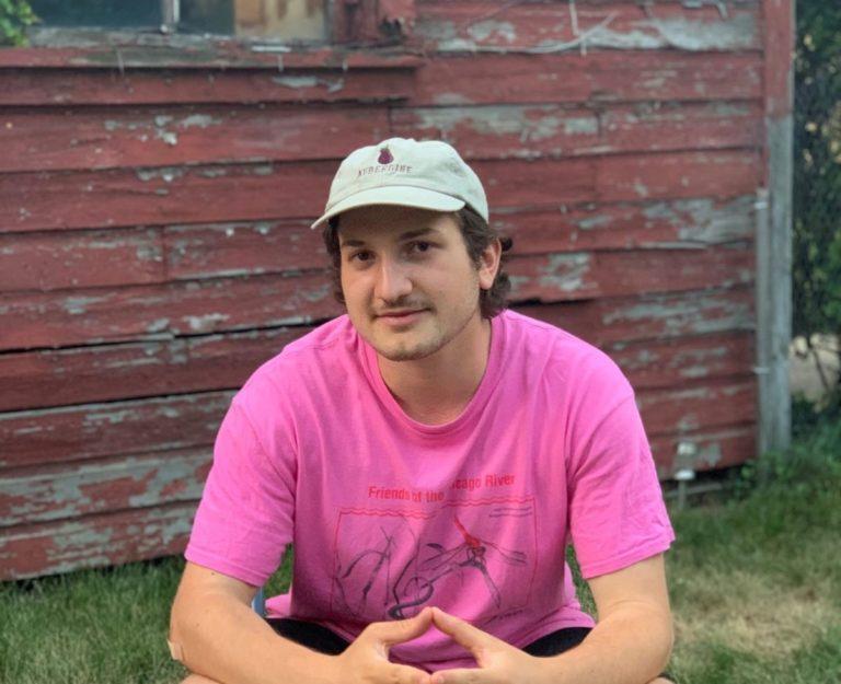 Zach Ben-Amots, wearing a pink T-shirt, looks into the camera.