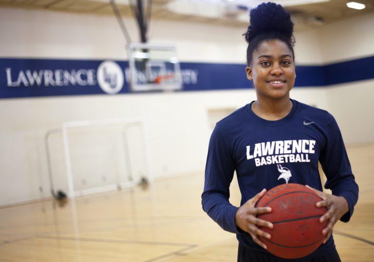 Shonell Benjamin, wearing a Lawrence basketball shirt, stands holding a basketball.