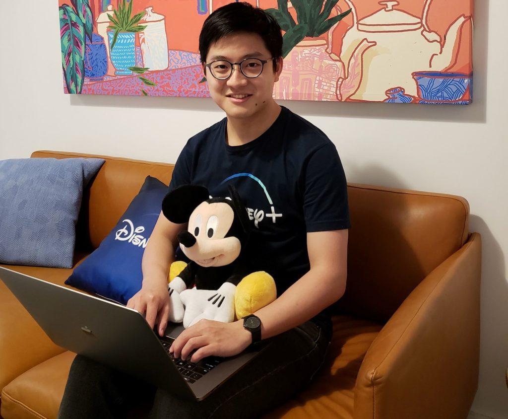 Kir-Sey Fam ’19, a computer science major, sitting on a couch with laptop and smiling.