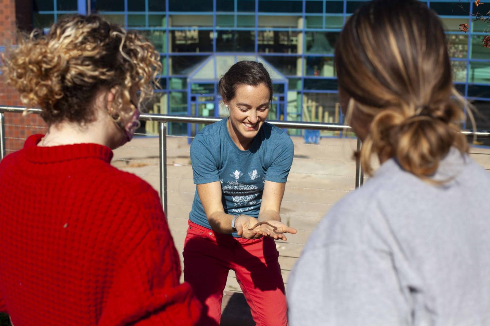 Professor showing students a worm during an Environmental Science lab.