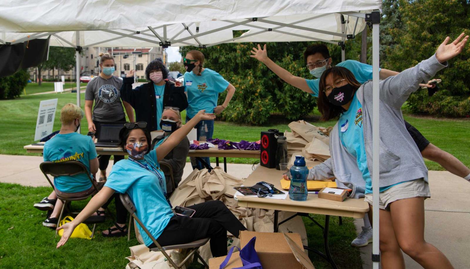 Group of community advisors pose for camera under white tent