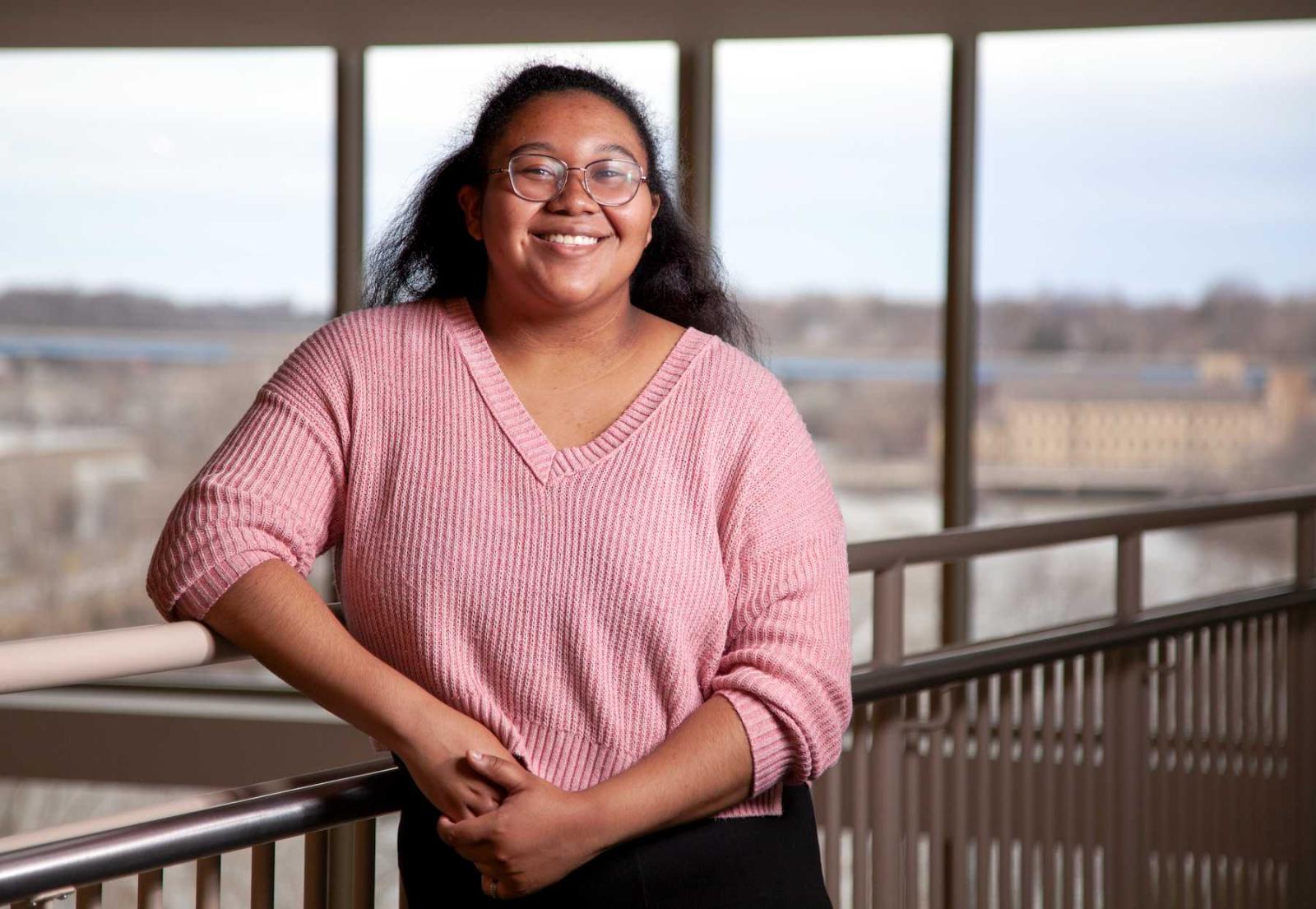 Imani Williams poses for a photo in front of large windows in the Warch Campus Center.