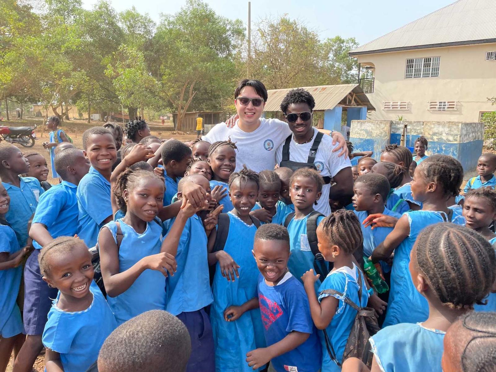 Lawrence Sid Short and Tomi Oladunjoye pose for a photo with a group of FAWE students outside the school.