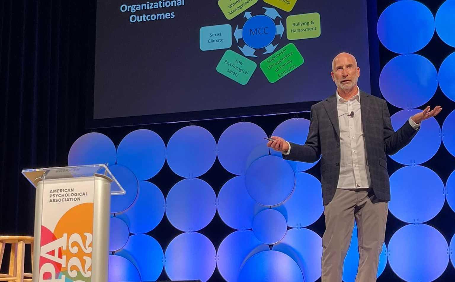 Peter Glick gestures on stage while delivering the keynote address at the American Psychological Association national convention in Minneapolis.