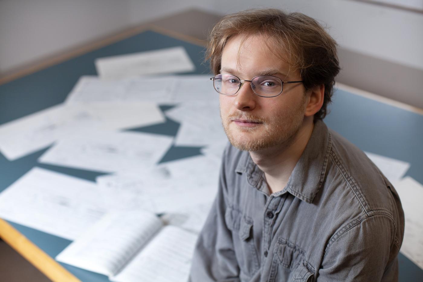 Brock Daumler poses with some of his music compositions in the background.