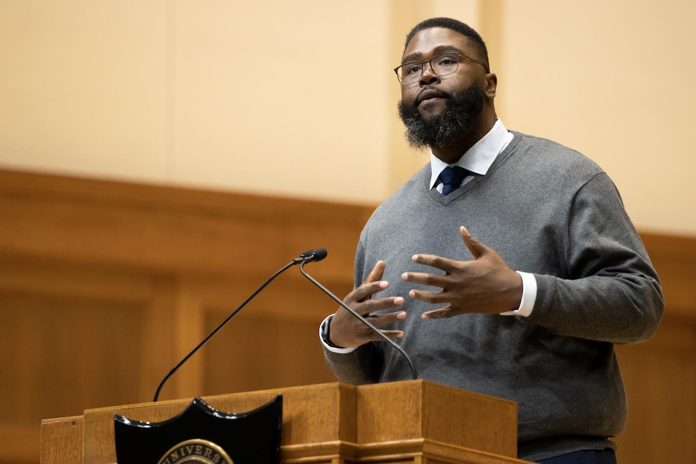 Dr. Anthony Jack gestures while speaking at the podium on the Memorial Chapel stage.