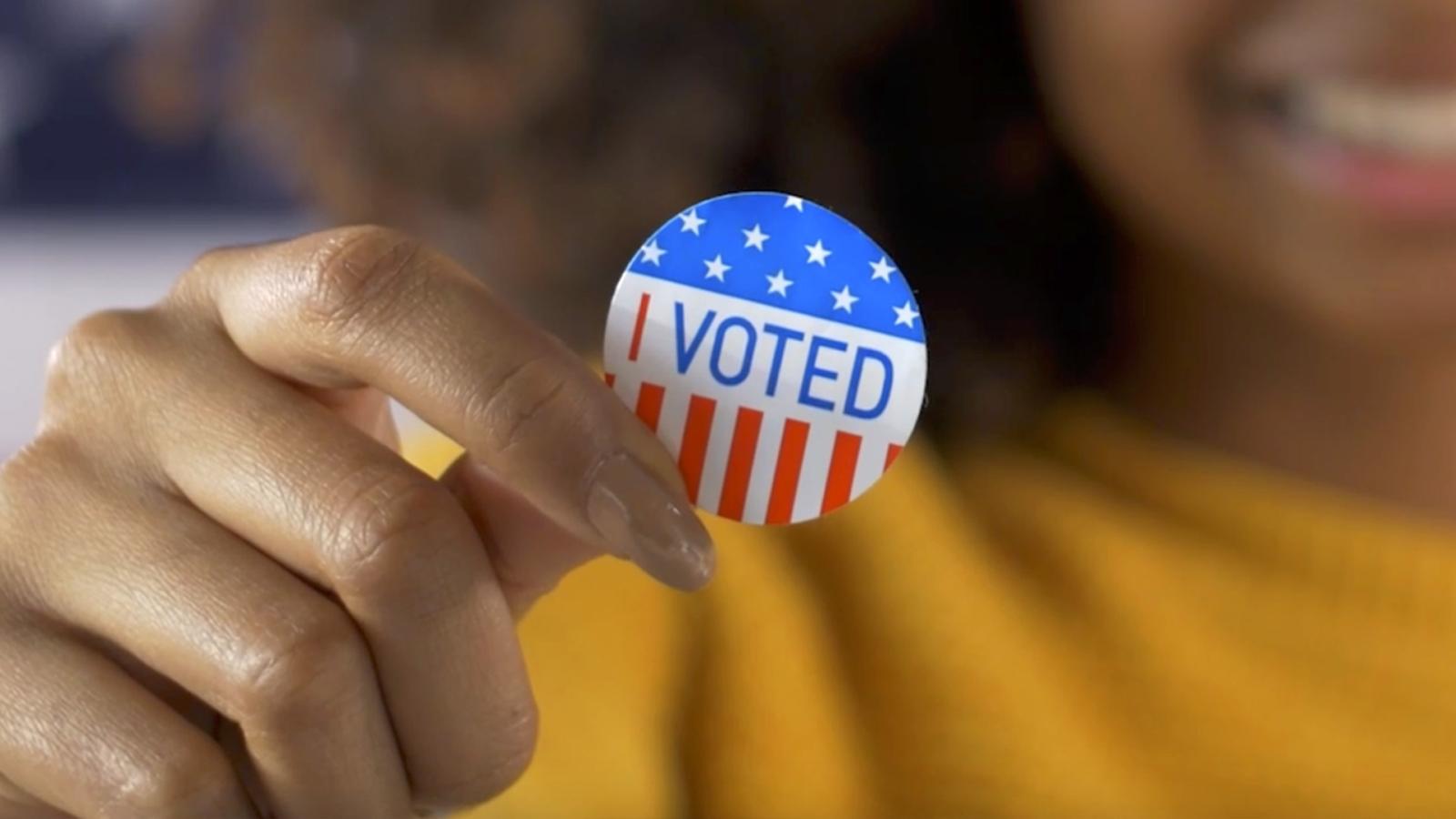 Closeup of hand holding I voted sticker