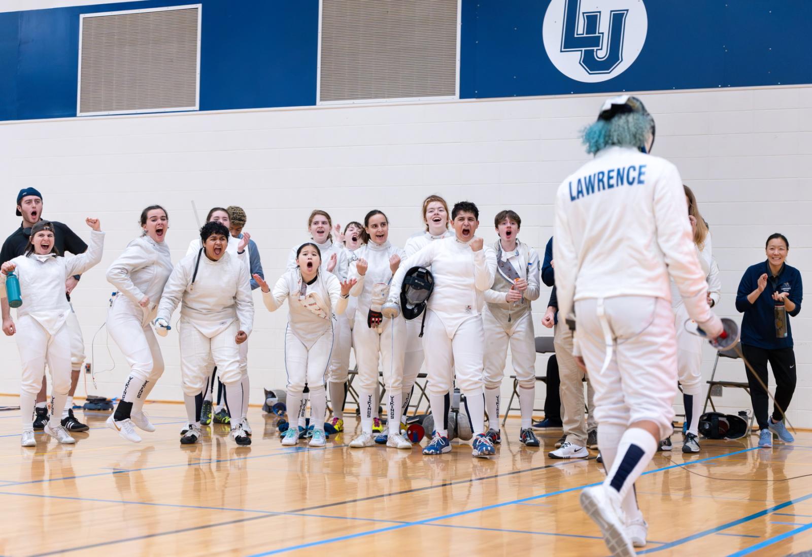 Members of the Lawrence fencing team react with joy at a win in the Wellness Center gym.