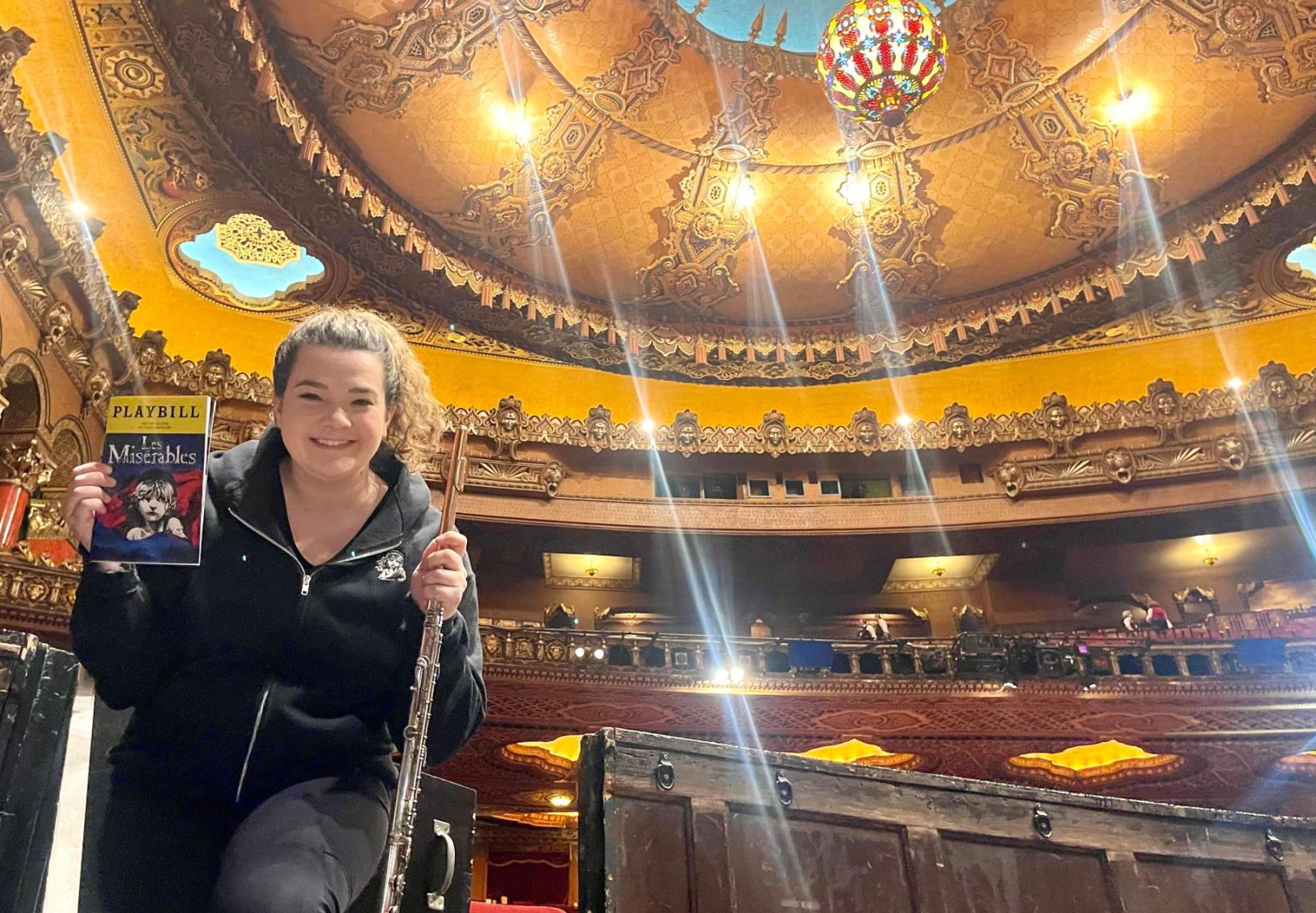 Schuyler Thornton '14 holds a playbill for "Les Miserables" and her flute as she poses for a photo on stage. 
