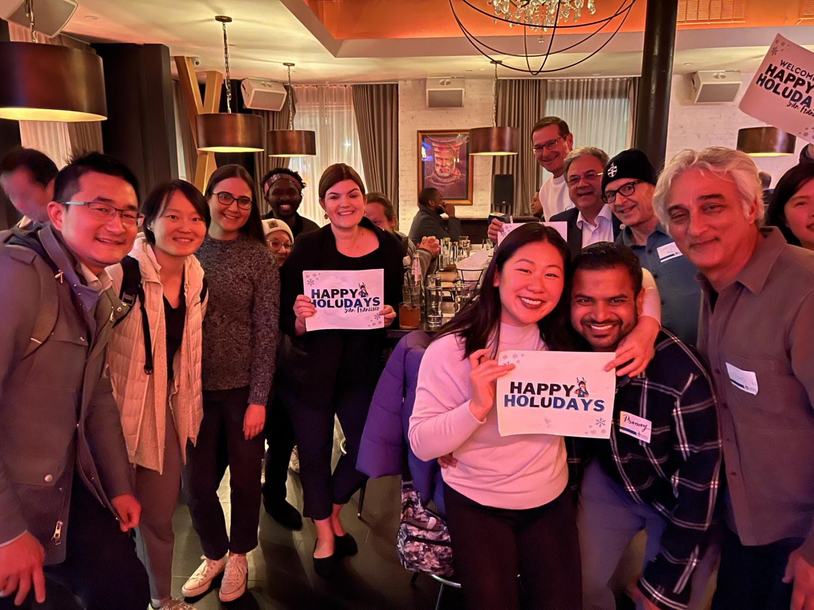 Lawrence alumni hold Happy HoLUdays signs at a gathering in San Francisco.