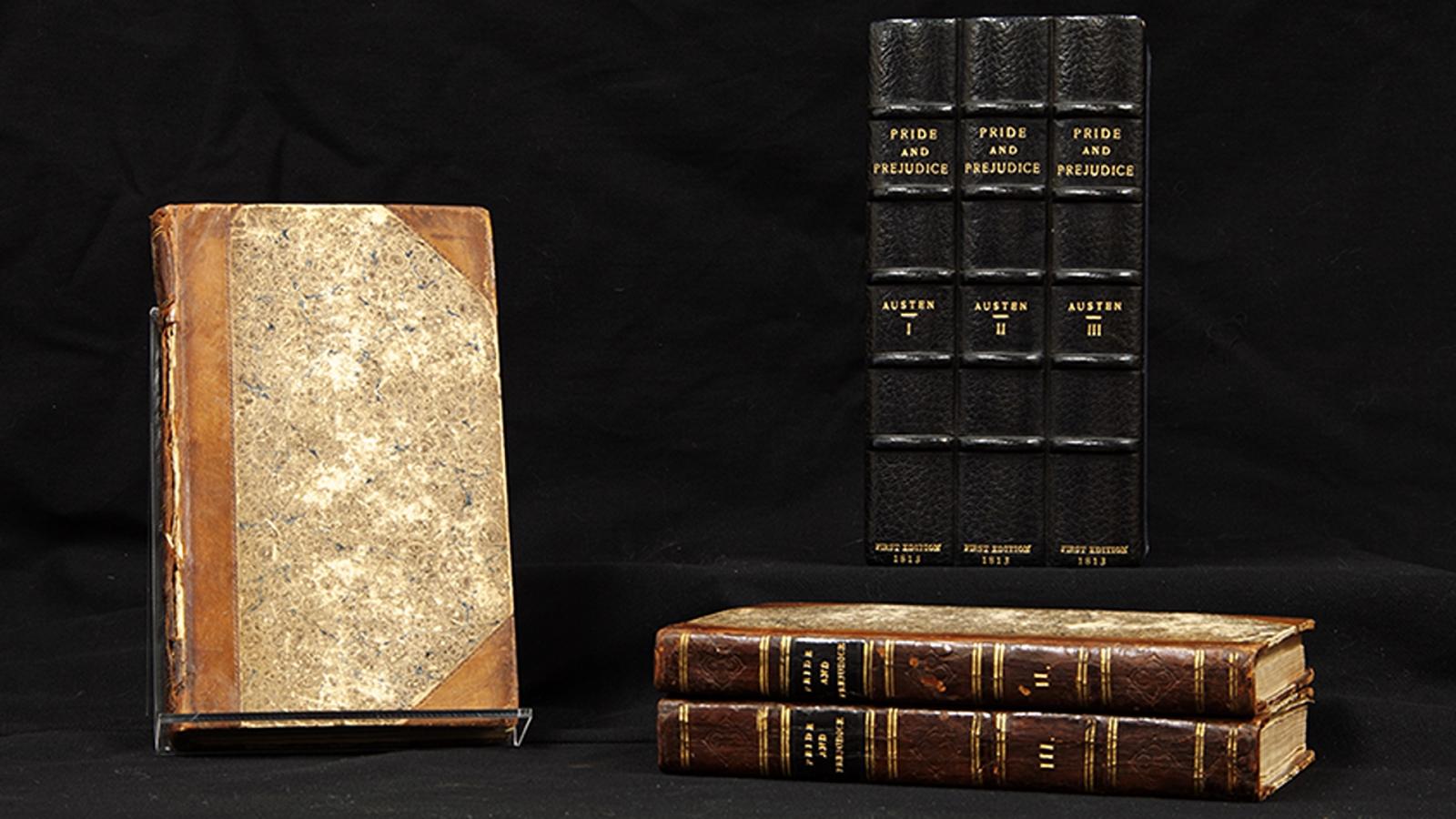 First edition of Jane Austen's Pride and Prejudice, in three volumes with brown marbled covers and a black case for the volumes labeled "AUSTEN," numbered I, II, III, with "1813" printed beneath in gold. All against a black background. 