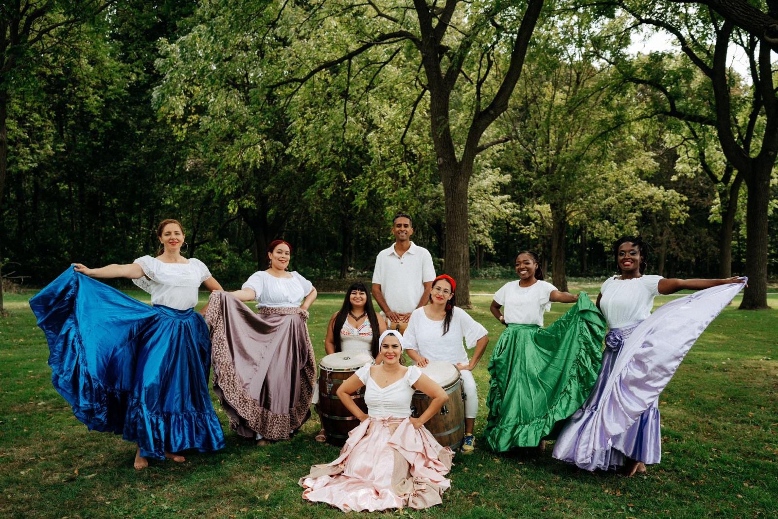 A group of dancers and musicians posing in a park.