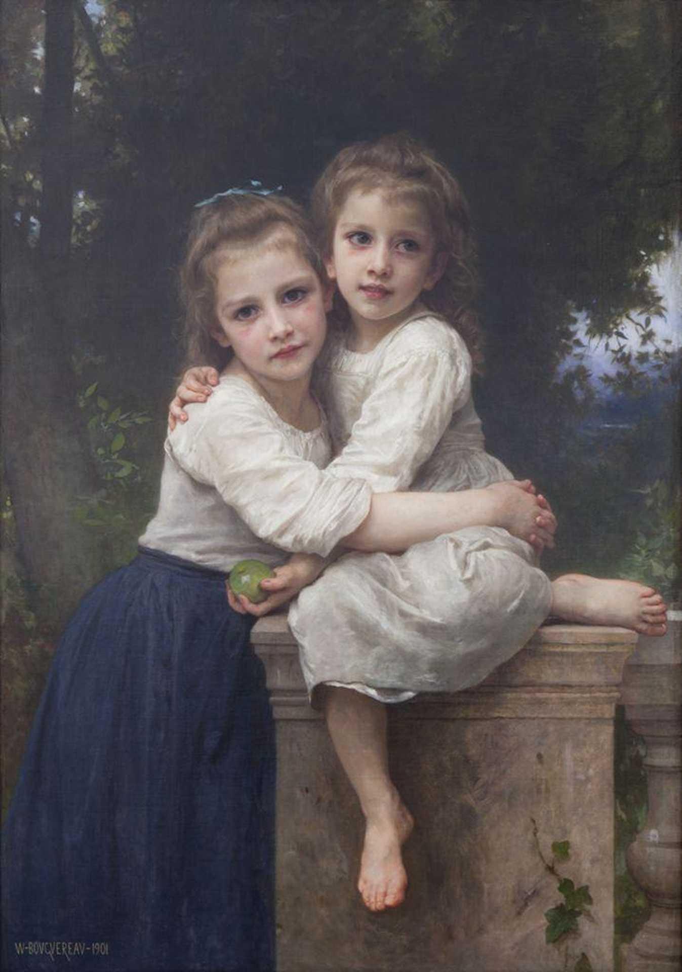 Two children in white clothing embrace while seated on a stone ledge in a wooded garden setting.