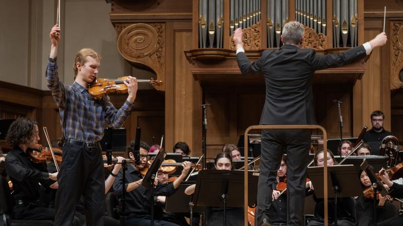 Violin soloist performing with orchestra.