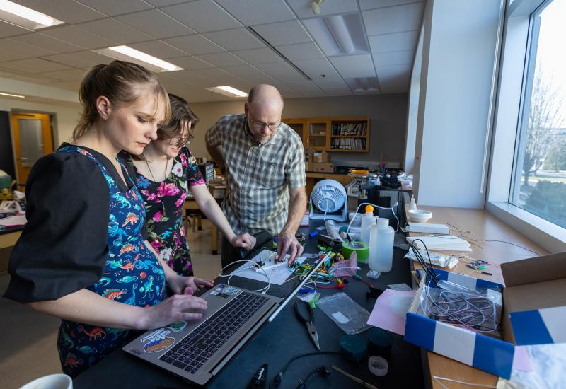 Geosciences professor Jeff Clark works with students Sydney Closson and Kat McClain in building spectrometers.