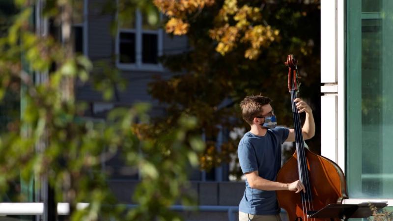 David Pickar ’23 plays an upright bass on the steps of Shattuck Hall