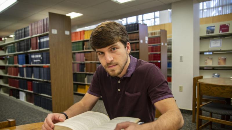 Nick Vaporciyan sits at a wooden table and looks up from a book.