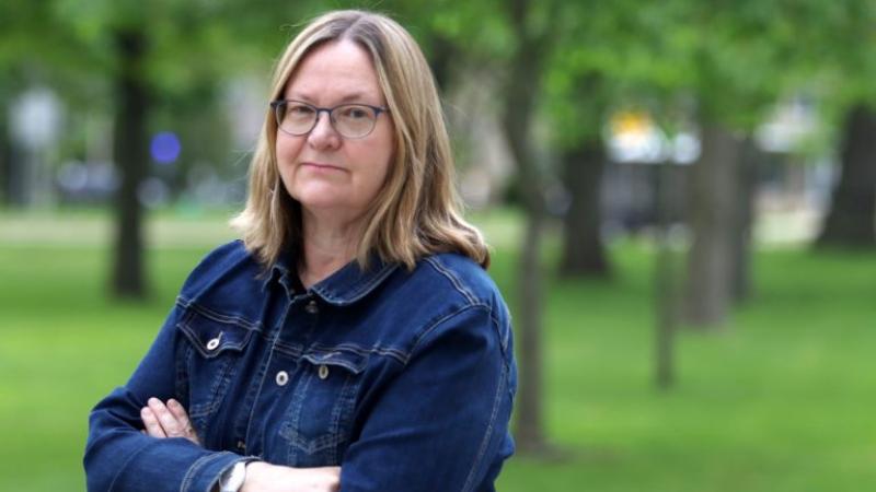 Claudena Skran, standing with her arms crossed in a jean jacket, stands on Main Hall Green.