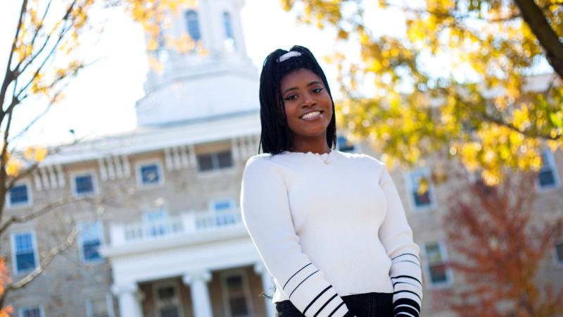 Kelsi Bryant standing outside Main Hall on a sunny fall day.