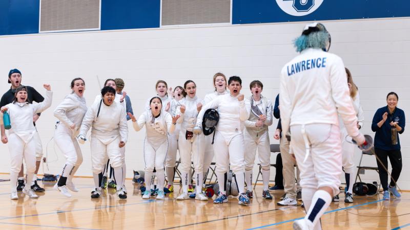 Members of the Lawrence fencing team react with joy at a win in the Wellness Center gym.