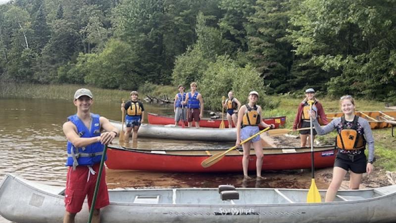 Students standing by canoes on a lakeshore at 2024 Sylvania Land and Sea Pre-orientation experience 