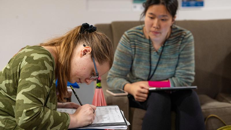 A student doing homework under the guidance of a student tutor.