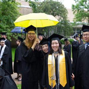 Four Lawrentians smile and pose for the camera. One holds an umbrella.