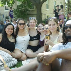 Seven students sit in a semi-circle on the lawn outside the Quad.