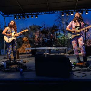 A two-person band perform onstage during early evening.