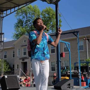 Student with mic in hand performs onstage on the Quad.