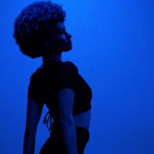 Senior Chloe Thomas is silhouetted against a backdrop of blue lights during a Cultural Expressions performance in Warch Campus Center.